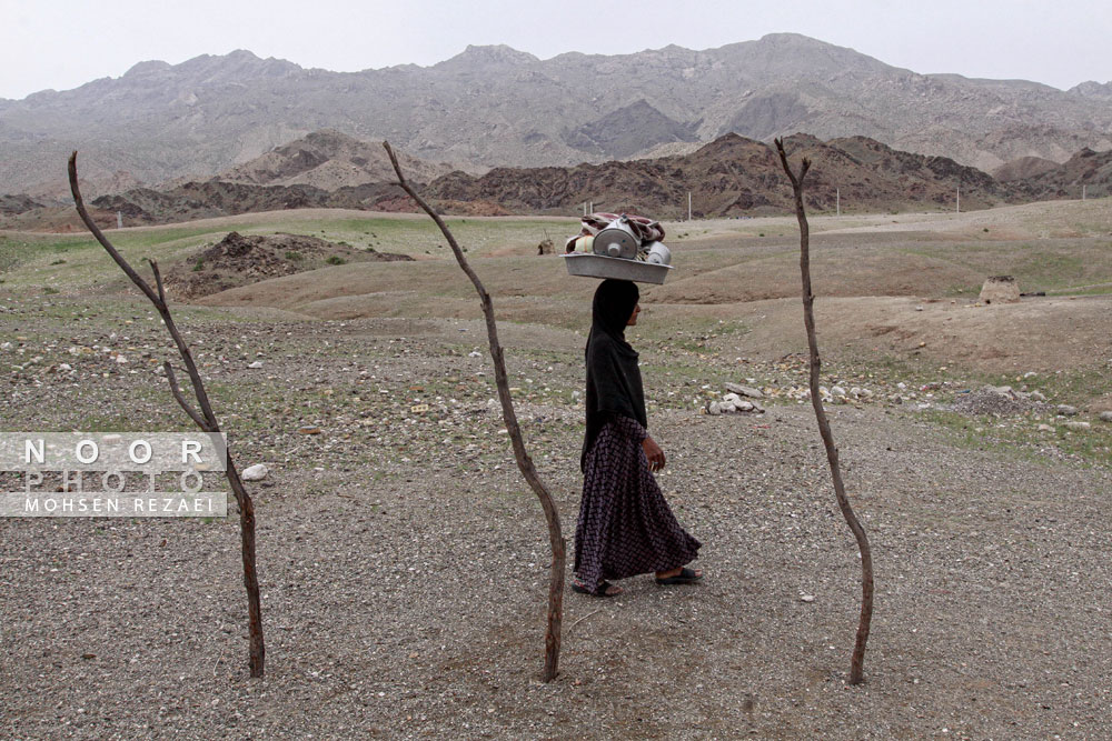 بازگشت زن از شستشوی ظروف در کنار رودخانه کم آب و از اهالی جنوب کرمان 