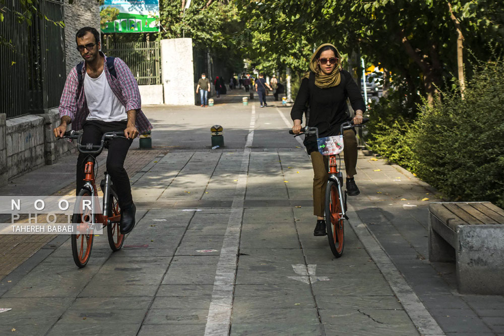 دوچرخه سواری مرد و زن ایرانی در معابر خیابان های دانشگاه تهران