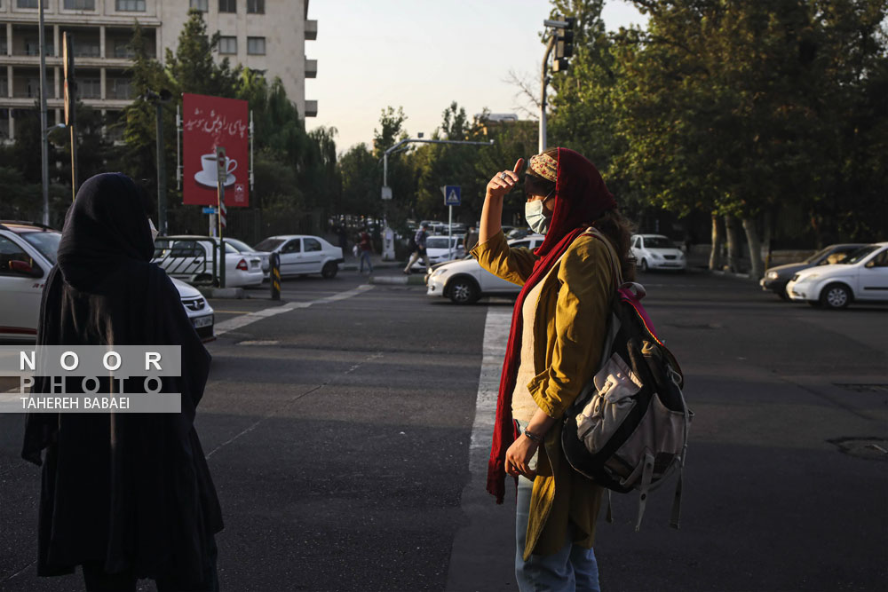 انتظار مسافر برای تاکسی در خیابان انقلاب تهران
